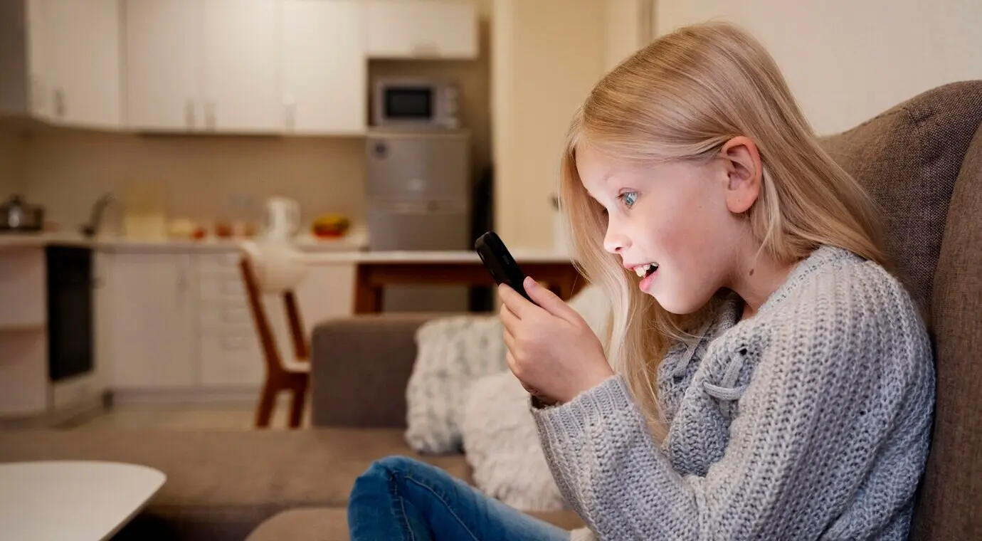 A little girl is using a smartphone at home.